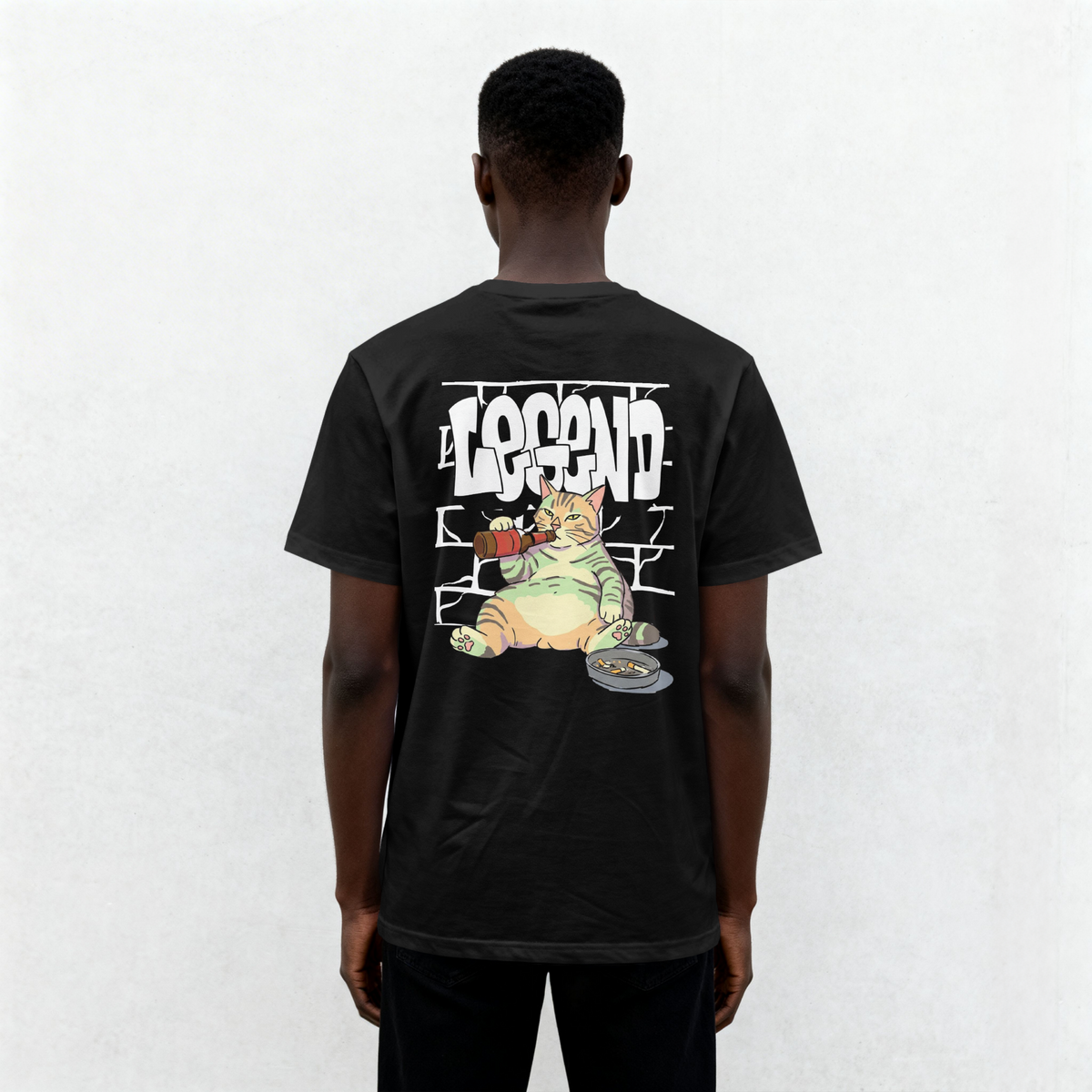 Back view of a black streetwear t-shirt featuring a funny beer drinking chubby cat sitting by a brick wall with LEGEND graffiti text