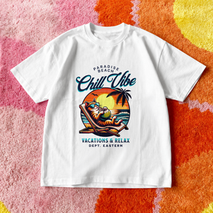 A crisp white relaxed fit streetwear t-shirt with a colorful Paradise Beach sunset and a cat sipping coconut drink