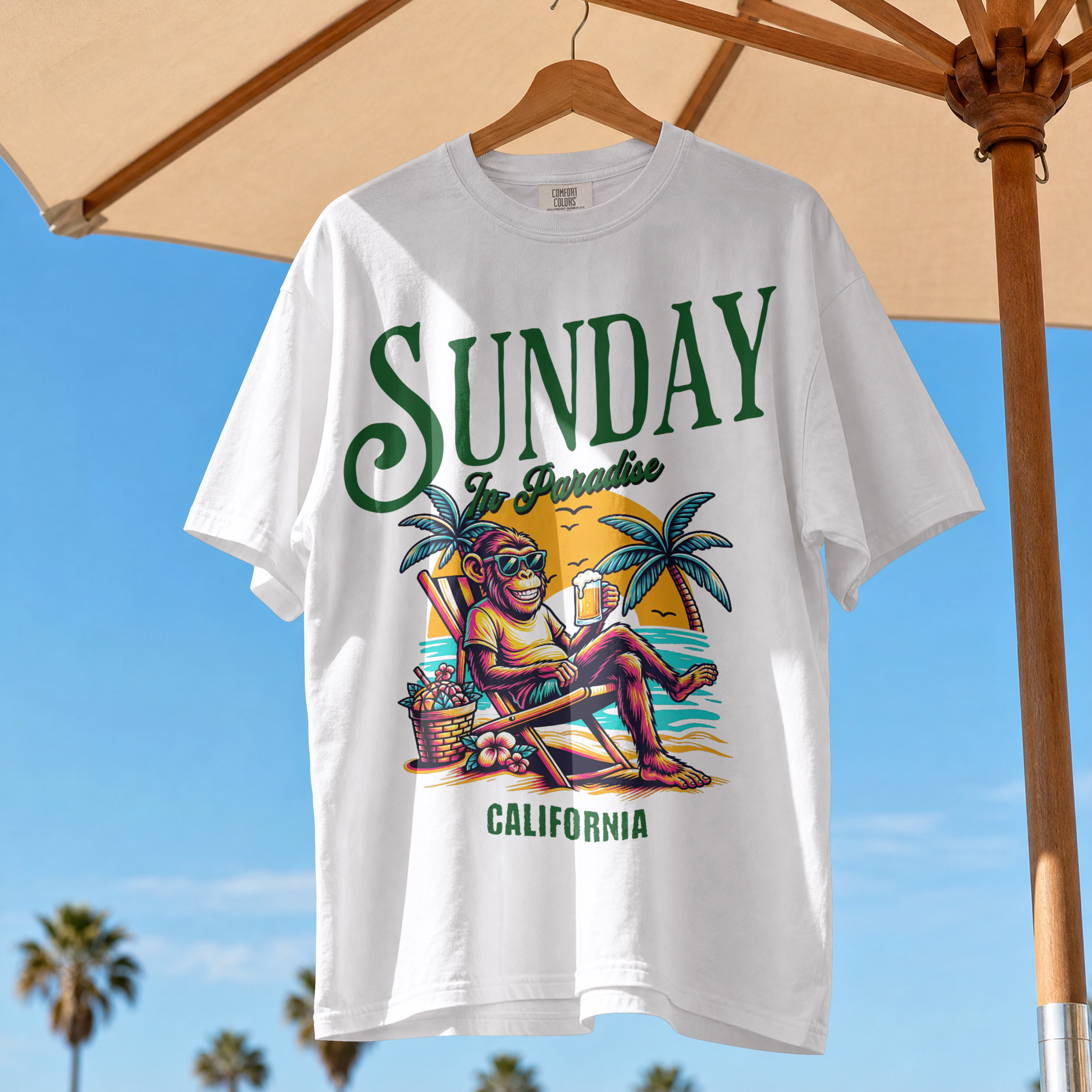 Model wearing a white relaxed fit t-shirt with a vintage green Sunday in Paradise slogan and a colorful beach sunset monkey graphic