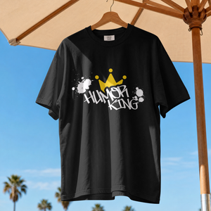 showing a black streetwear t-shirt featuring a handwritten style Humor King slogan and a clean yellow crown logo